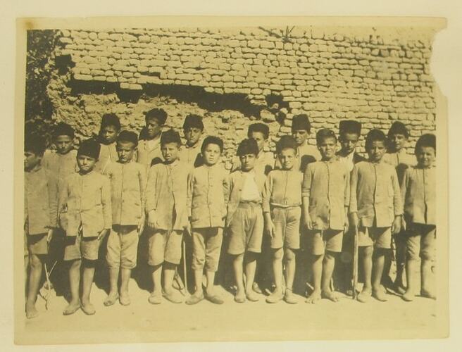 Group of refugee boys lined up in matching outfits.