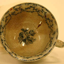 Inside of cracked teacup with vineleaf design.