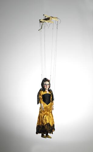Puppet wearing yellow and black dress, front view.