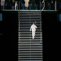 Back view of John Landy in white ascending staircase. HRH Queen Elizabeth II at top of stairs wears yellow.