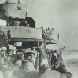Soldiers on the deck of a military battleship, ocean in the background.