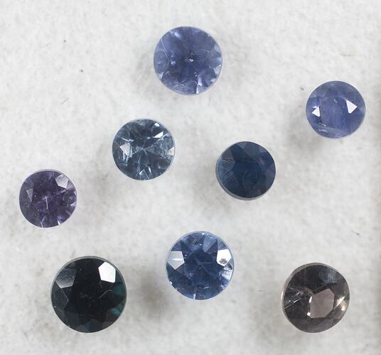 Eight round faceted sapphires, various shades of blue.