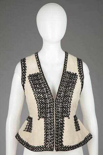 Cream vest with black embroidered border.