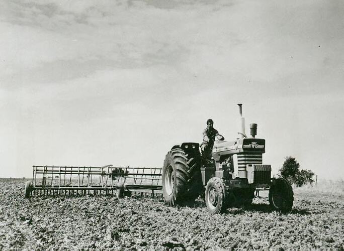 Front view of a man driving a tractor coupled to a scarifier.