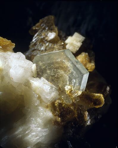 Clear hexagonal crystal growing out of white crystals.