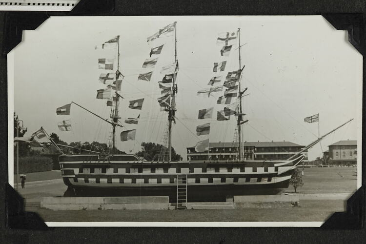 Ship in field with concrete blocks surrounding and flags on masts.