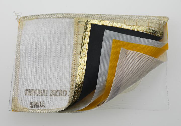 Rectangular fabric sample with six layers. White, gold, black, white, yellow, white.