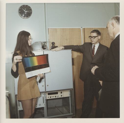 Woman holding colour chart with two men.