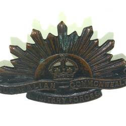 Front side of badge with rising sun motif.