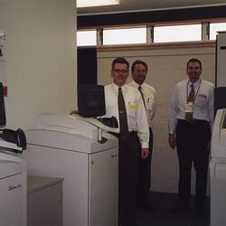 Three men with photographic processing machines.
