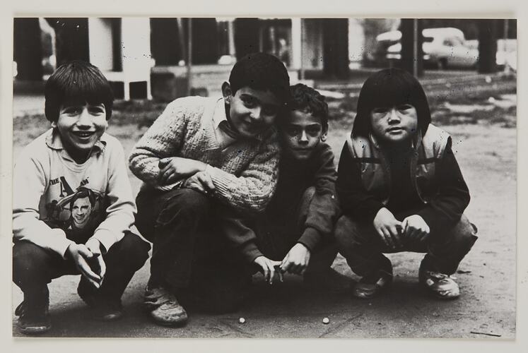 Four young boys playing a marbles game.