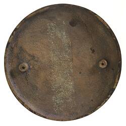 Back of a round bronze medal with raised attachment holes at either side.