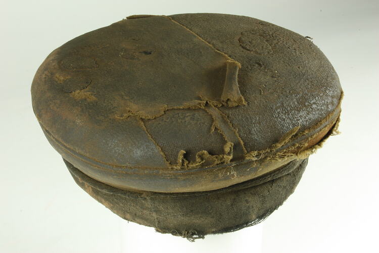 Three-quarter overhead view of old battered nightsoil collector's khaki flat top cap