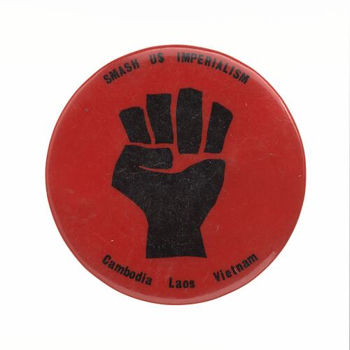 Round red badge with black fist in centre. Black text top and bottom.