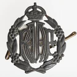Metal badge with stylised RAAF letters framed by wreath with crown atop.