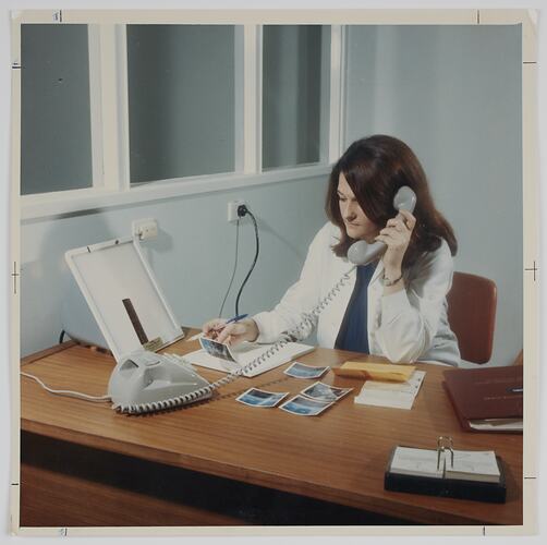 Woman on the phone behind a desk.