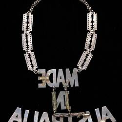 Back of metal necklace, 'MADE IN AUSTRALIA' hangs inverted from 3 rectangular diamante plates on each side.