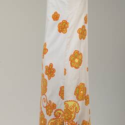 Right side long sleeveless white cotton dress. Orange and yellow floral printed pattern.