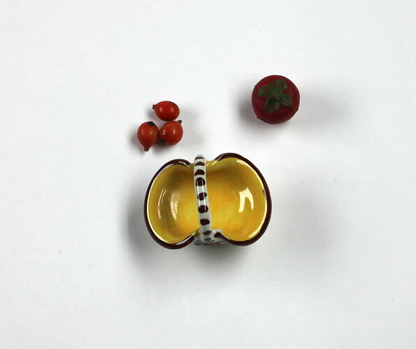 Top view yellow fruit basket. Three oranges, one tomato.