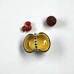 Top view yellow fruit basket. Three oranges, one tomato.