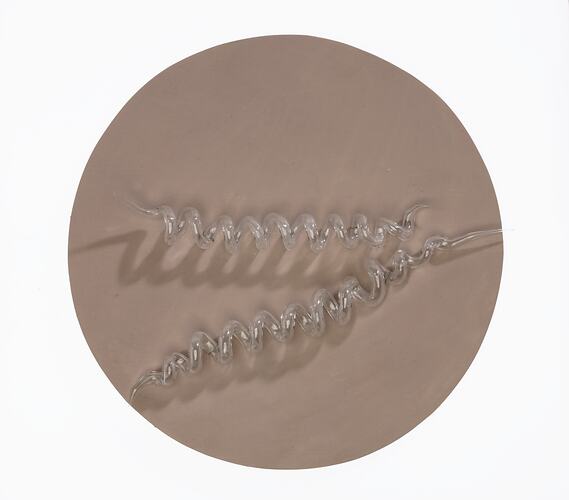 Light brown disc with clear glass capsule-shaped pieces on top.