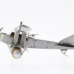 Model of a bi-plane made mostly of aluminium sheet metal. It has two pairs of wheels at front. Left profile.