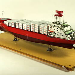 Container ship with red hull three quarter view.