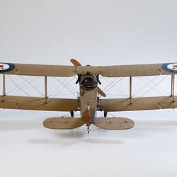 Model biplane aeroplane painted mustard brown with grey engine. Back view.