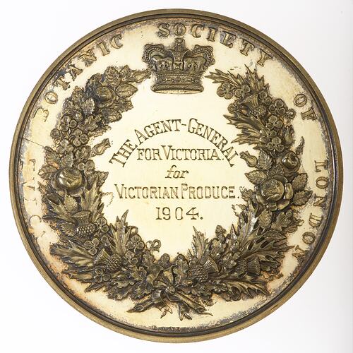 Round medal with text engraved within crowned wreath of roses, thistles and shamrocks.