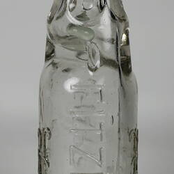 Clear glass bottle with raised inscription.