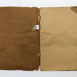 Worn open booklet with brown cover at left and off-white page at right. Holes, stained.