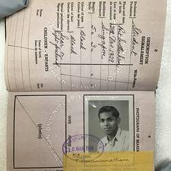 Open passport with white pages and black printing. Handwritten text and image of man smiling.