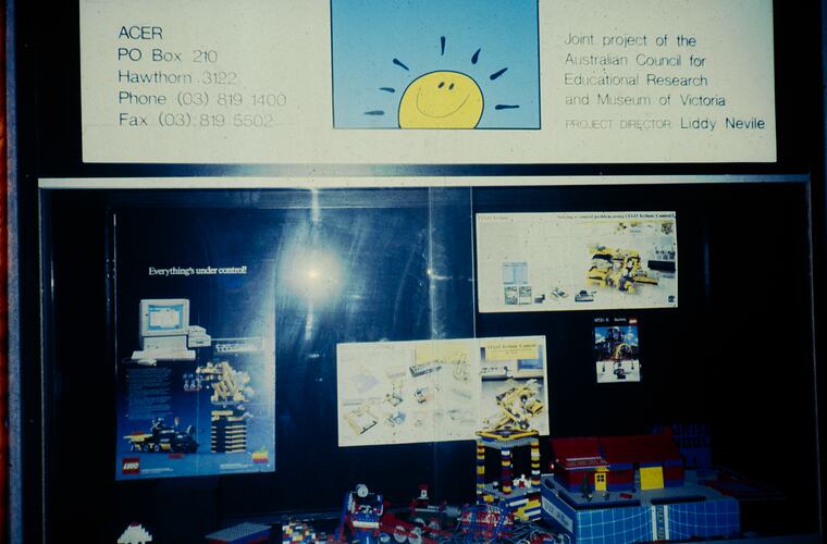 View of a museum showcase containing Lego constructions, leaflets and a Sunrise logo.