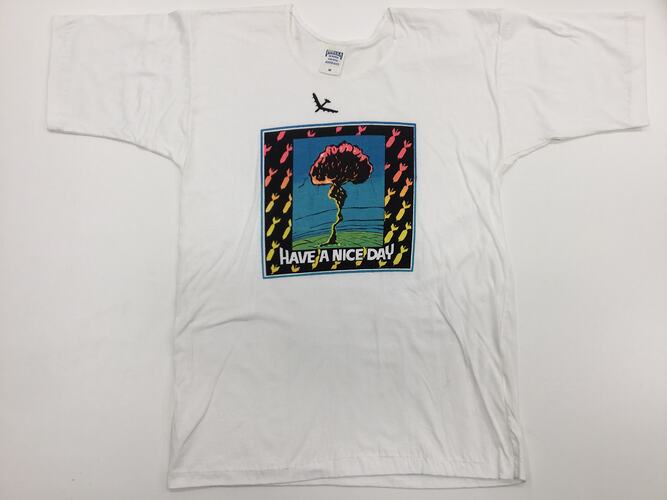 White t-shirt with colourful printed mushroom cloud, framed by fish. Text below.