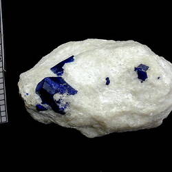 Rounded white rock with blue crystals on surface.