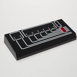 Rectangular black plastic computer control. White lines and lights on top.