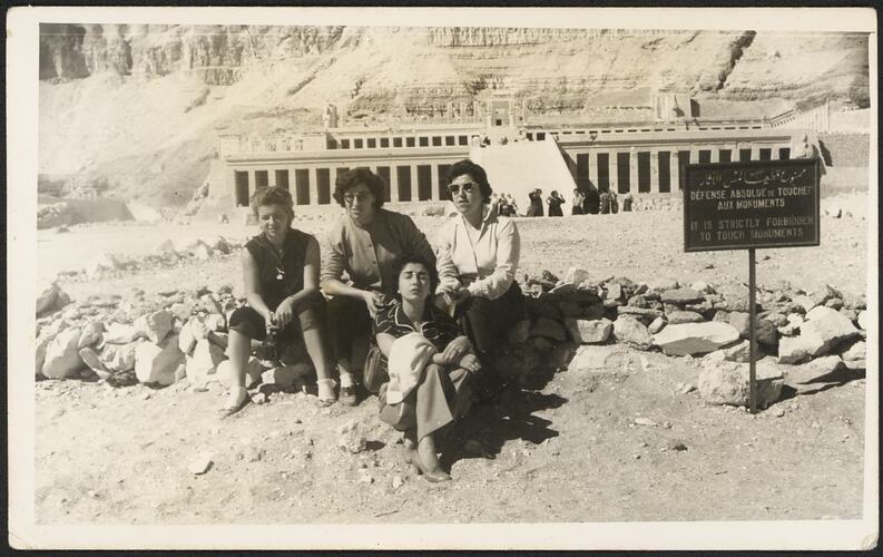 Four people sitting in front of Egyptian archaeological site.