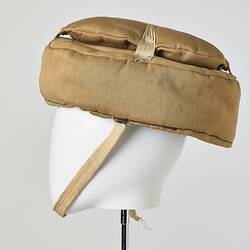 Beige cotton cap, padded, with strap. Profile.