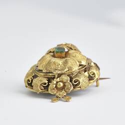 Round gold brooch with gold border and green paste.