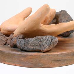 Side view of sculpture of two clay hands.