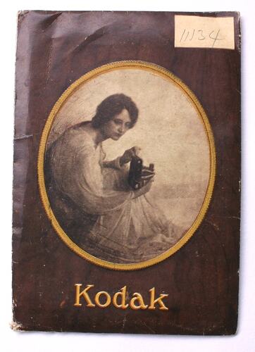 Paper Kodak wallet with brown and white woman holding box browny camera. Numbered 11/34.