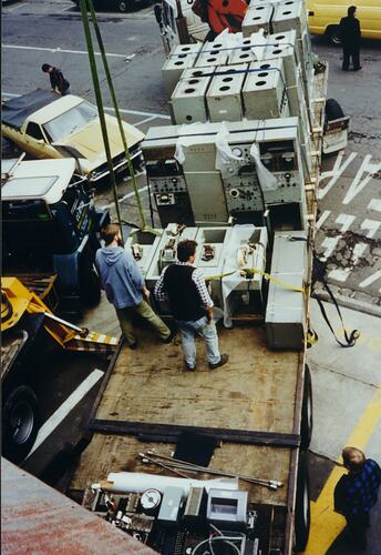Two men on truck with large machinery sections.