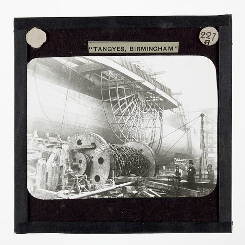Men in top hats next to a very large ship.