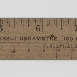 Wooden ruler showing inches and centimetres.