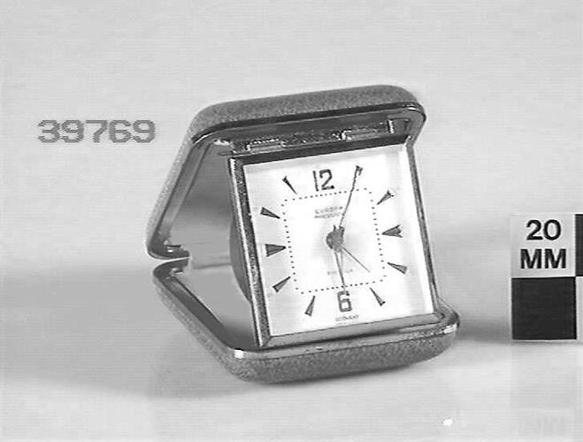 Clock in hinged metal and leather case.