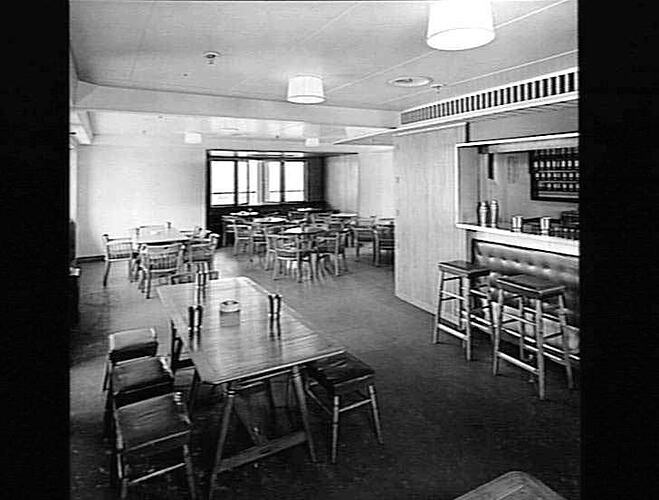 Ship interior. Bar with stools. Wooden round chairs and tables in background.