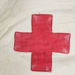 White cotton fabric with large red cross, close-up view.