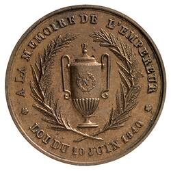 Round medal, central urn framed by wreath. Text around.