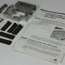 Metal brackets, black plastic pieces, white page with black printing.