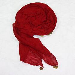 Red scarf-like headdress with metal discs along edges.
